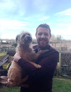 Ken is holding his fluffy dog in arms