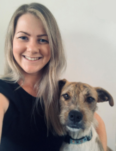 Woman holding in her left arm a brown cross-breed dog