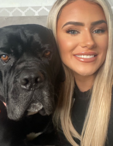 Blond woman standing nearby her Italian Mastiff dog