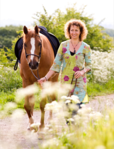 woman pulling a horse across a field